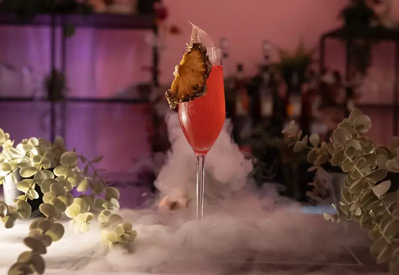 Pink P.Louise cocktail with dehydrated garnish and dramatic dry ice mist, a camera ready signature serve