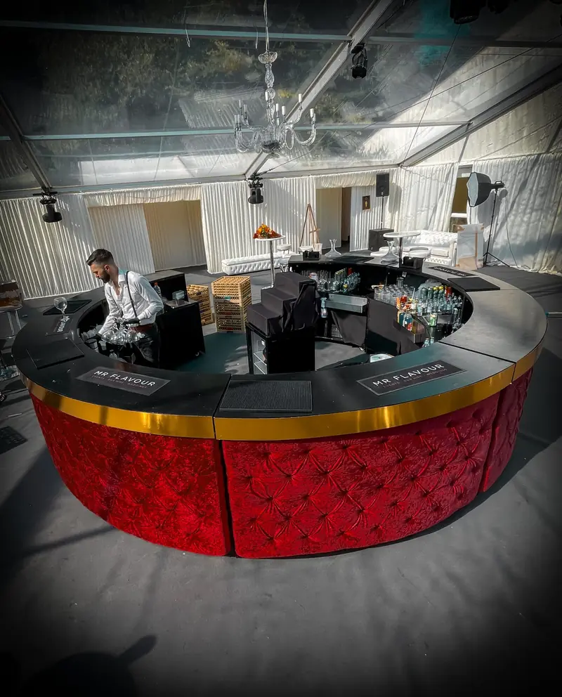 Circular bar with red Chesterfield panels and a bartender at work, built by the Mr Flavour team