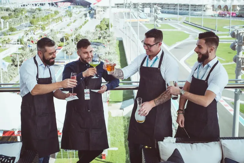 Four Mr Flavour mixologists on a Yas Marina suite terrace overlooking the circuit at the Abu Dhabi Grand Prix