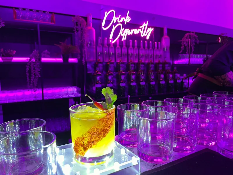 Spicy margarita on a lit plinth beneath the purple Drink Differently neon