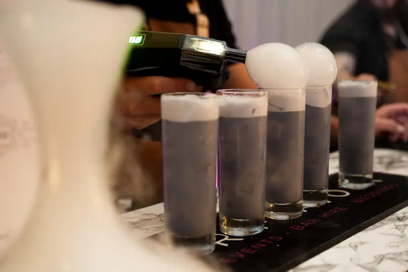 Mixologist topping cocktails with smoke bubbles from a flavour blaster
