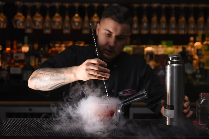Mixologist stirring a liquid nitrogen cocktail as vapour rolls across the bar